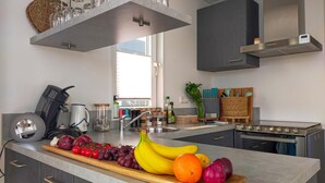 Eine moderne Küche mit Kochinsel, Edelstahlgeräten und einer Auswahl an Obst und Gemüse.