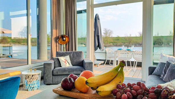 Ein modernes Wohnzimmer mit einer Couch, einem Esstisch mit Stühlen und einer Obstauslage.