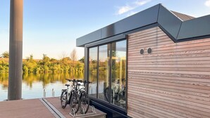 Ein modernes Gebäude mit Holzfassade und großen Fenstern, die auf ein ruhiges Gewässer blicken.