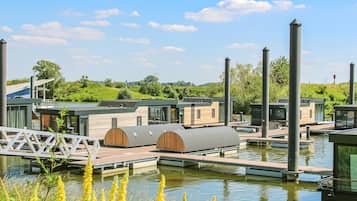 Een modern drijvend hotel met meerdere hutten, een houten dek en een brug die de hutten verbindt.