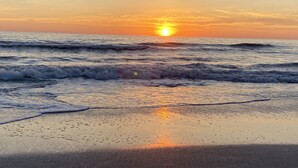 Ein Strand mit Wellen und einem Sonnenuntergang.