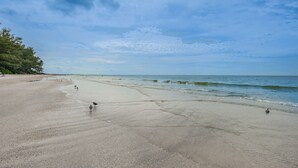 Ein weiter Sandstrand mit sanften Wellen und blauem Himmel.