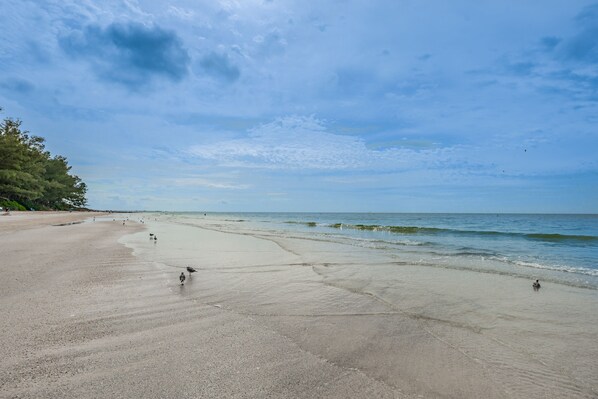 A wide beach with gentle waves and a clear sky.