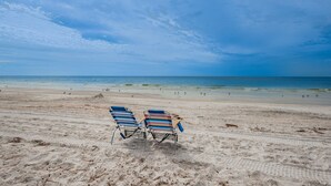 Ein Strand mit zwei Liegestühlen und Sand.