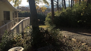 A house with a balcony, surrounded by trees and a gravel path.