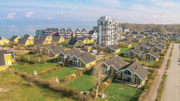 A residential area with multiple two-story houses, a central building with a unique architectural design, and a clear view of the surrounding landscape. - Nice home in Rechlin with sauna (Rechlin)