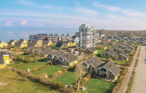 A residential area with multiple two-story houses, a central building with a unique architectural design, and a clear view of the surrounding landscape.