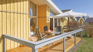 A wooden house with a covered patio, outdoor seating, and a white umbrella. - Nice home in Rechlin with sauna (Rechlin)