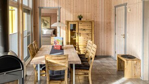 A wooden-paneled room with a dining table, chairs, a cabinet, and a radiator. - Nice home in Rechlin with sauna (Rechlin)