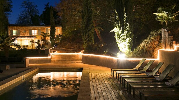 A nighttime swimming pool area with lounge chairs and a stone structure. - Magnificent restored farmhouse in Crillon-le-Brave with swimming pool  (CRILLON LE BRAVE)