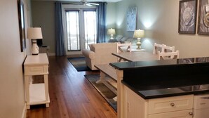 A modern kitchen with white cabinetry, a black countertop, and a dining area with a table and chairs. - Beautiful Condo!!  Boutique Complex,  Private Beach Access,  Pool (Santa Rosa Beach)