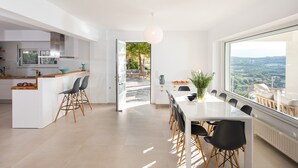 A modern kitchen with a large island, a dining area with a view, and a spacious living area. - KEA, above the sea, superb views, near beach. (Almyrida)