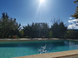Ein Schwimmbecken mit klarem, blauem Wasser, umgeben von Bäumen und blauem Himmel.
