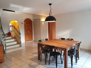 Ein Essbereich mit Holztisch und -stühlen, einer Treppe und einer Holztür.