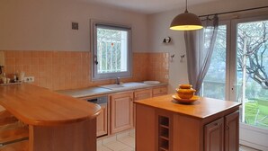 Una cocina con una isla de madera, un ventanal con vistas y una lámpara colgante.