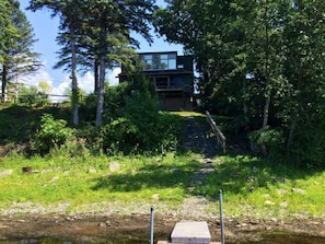 A modern building with a glass facade, surrounded by dense greenery and trees. -  Gone Fishing!  Is Pet Friendly! (South Hero)