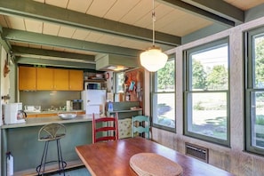 A kitchen with wooden cabinets, a dining table, and a hanging light fixture. -  Gone Fishing!  Is Pet Friendly! (South Hero)