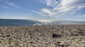 En strand med sand och vatten under en klar himmel.