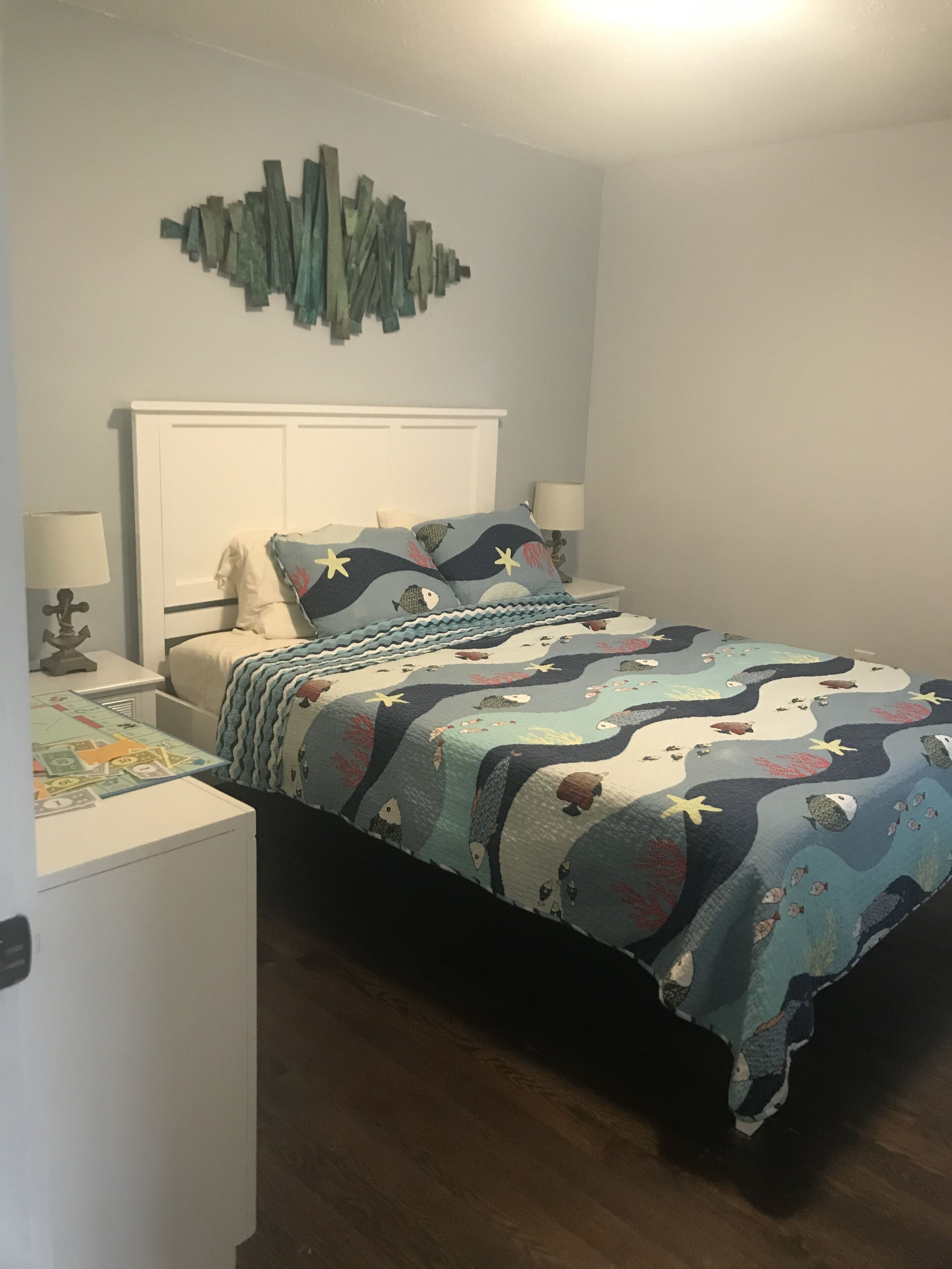 Un dormitorio con cama, dos mesitas de noche, un cuadro y una lámpara.
