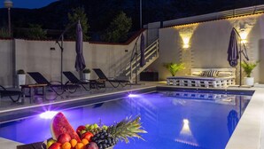 Une piscine avec des chaises longues et un panier de fruits.