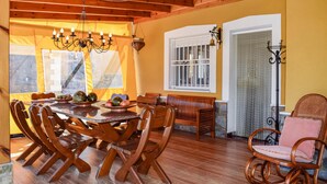 A wooden dining area with a table and chairs, a chandelier, and a window with bars. - Beautiful home in Orihuela (Orihuela)