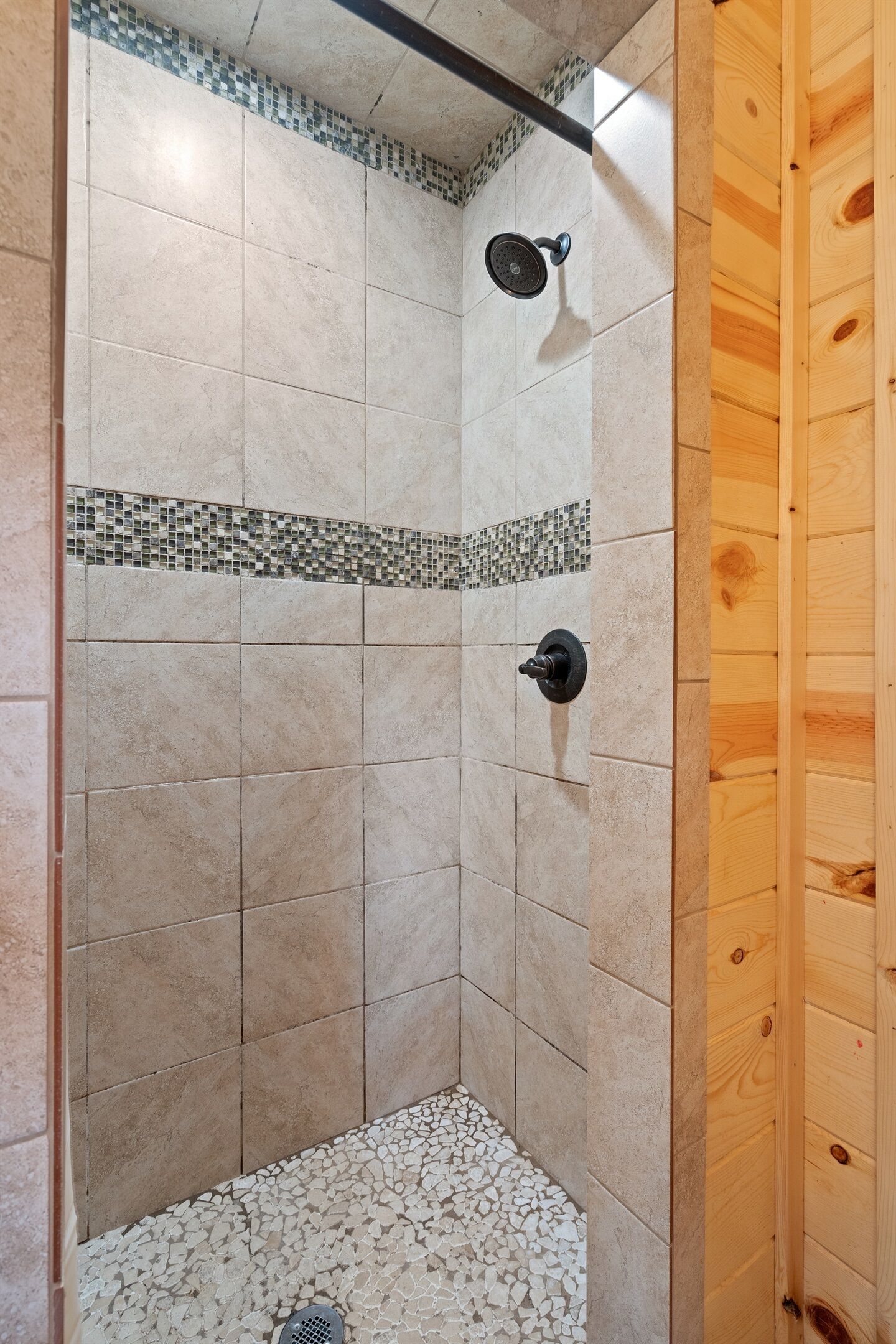Una ducha con paredes de azulejos y una puerta de madera.