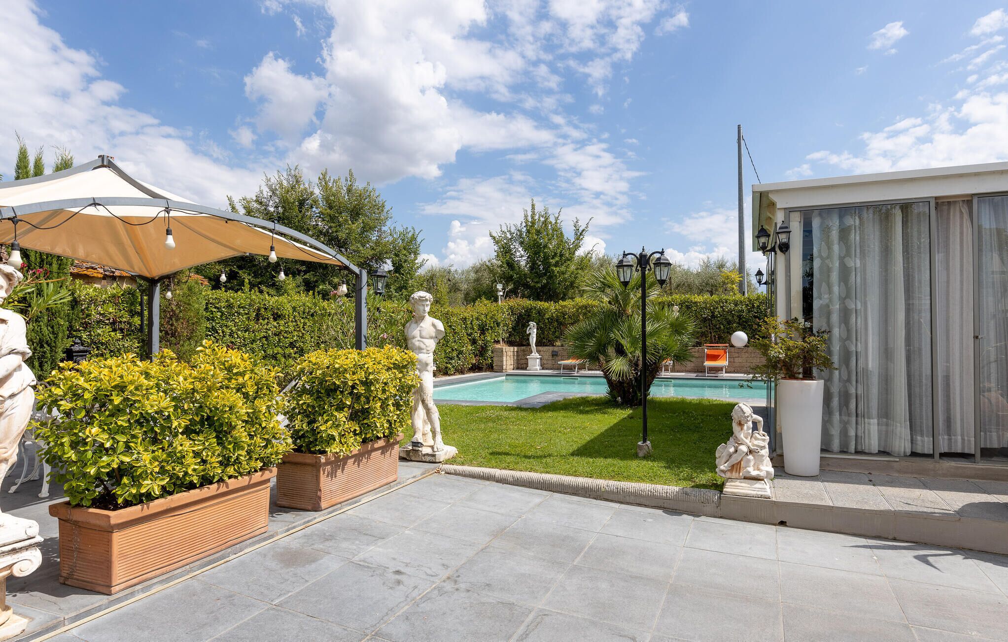 A garden with a pool, a gazebo, and statues.