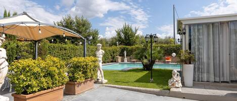 A garden with a pool, a gazebo, and statues.