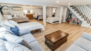 A spacious living room with a large sectional sofa, a wooden coffee table, and a staircase leading to an upper floor. - Beach House w/ a VIEW! Walk to Beach and Newport (Middletown)