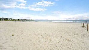 A wide sandy beach with a clear sky and distant houses. - Beach House w/ a VIEW! Walk to Beach and Newport (Middletown)