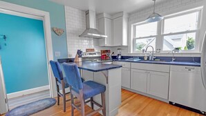 A kitchen with a blue door, white cabinets, a central island with bar stools, and a window providing natural light. - Beach House w/ a VIEW! Walk to Beach and Newport (Middletown)