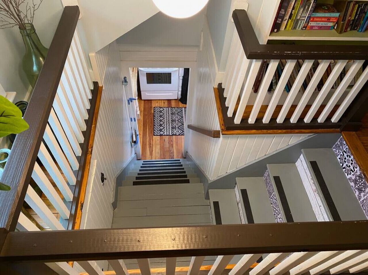 A staircase leading to a kitchen with a microwave, a rug, and a bookshelf.