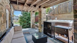 Un espace extérieur entouré de murs en pierre, avec un banc en pierre, une table à plateau en verre et un coin barbecue en bois.