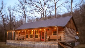 A wooden cabin with a porch, a red door, and a 'Welcome' sign. - BUCKEYE Creekside Cabin Ride to the trails from the cabin (Combs)