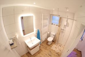 Bathroom features a sink, toilet, shower, and toiletries on a checkered tile floor.