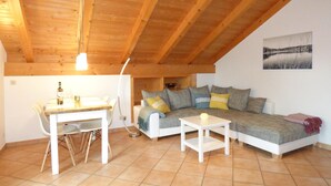 Una habitación acogedora con techo de madera, una mesa de comedor con sillas, un sofá con cojines y una mesita.