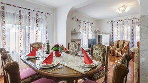 A dining area with a round table set for four, surrounded by chairs. There is a sofa and a television in the background. - Beautiful apartment in Pula with WiFi (Pula)