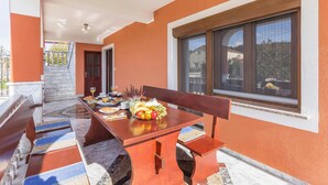 A dining area with a table set for breakfast, including fruits and pastries, and a bench. - Beautiful apartment in Pula with WiFi (Pula)