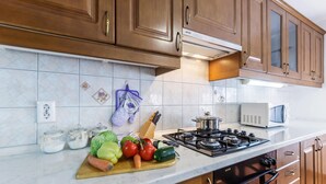 A kitchen with wooden cabinets, a gas stove, a microwave, and a cutting board with vegetables. - Beautiful apartment in Pula with WiFi (Pula)