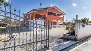 A two-story building with a red facade, a gated entrance, and a satellite dish. - Beautiful apartment in Pula with WiFi (Pula)