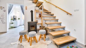 A modern interior with a wooden staircase, a fireplace, and a cozy seating area with stools. - Pet friendly home in Piscanovec (Piscanovec)