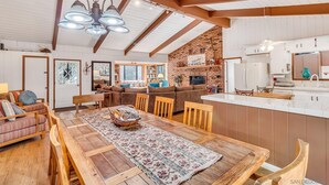 Amplia sala de estar con una mesa de comedor de madera, un conjunto de sofá y una cocina con un muro de acento de ladrillo.