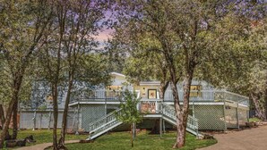 Un edificio con un espacio exterior cubierto, una escalera y un jardín vallado.