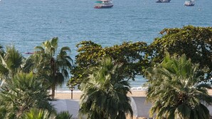 A beach with palm trees and boats on the water. - The Chezz Condominium by Patsamon (Pattaya)