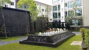 A modern outdoor area with a water feature, steps, and a building in the background. - The Chezz Condominium by Patsamon (Pattaya)