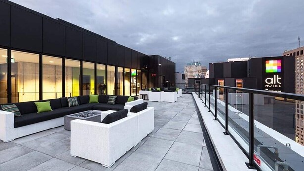 A rooftop terrace with outdoor seating, a glass railing, and a view of the city skyline. - Cozy Skyline Entire Condo in Downtown - Across from Bell MTS Centre (Winnipeg)