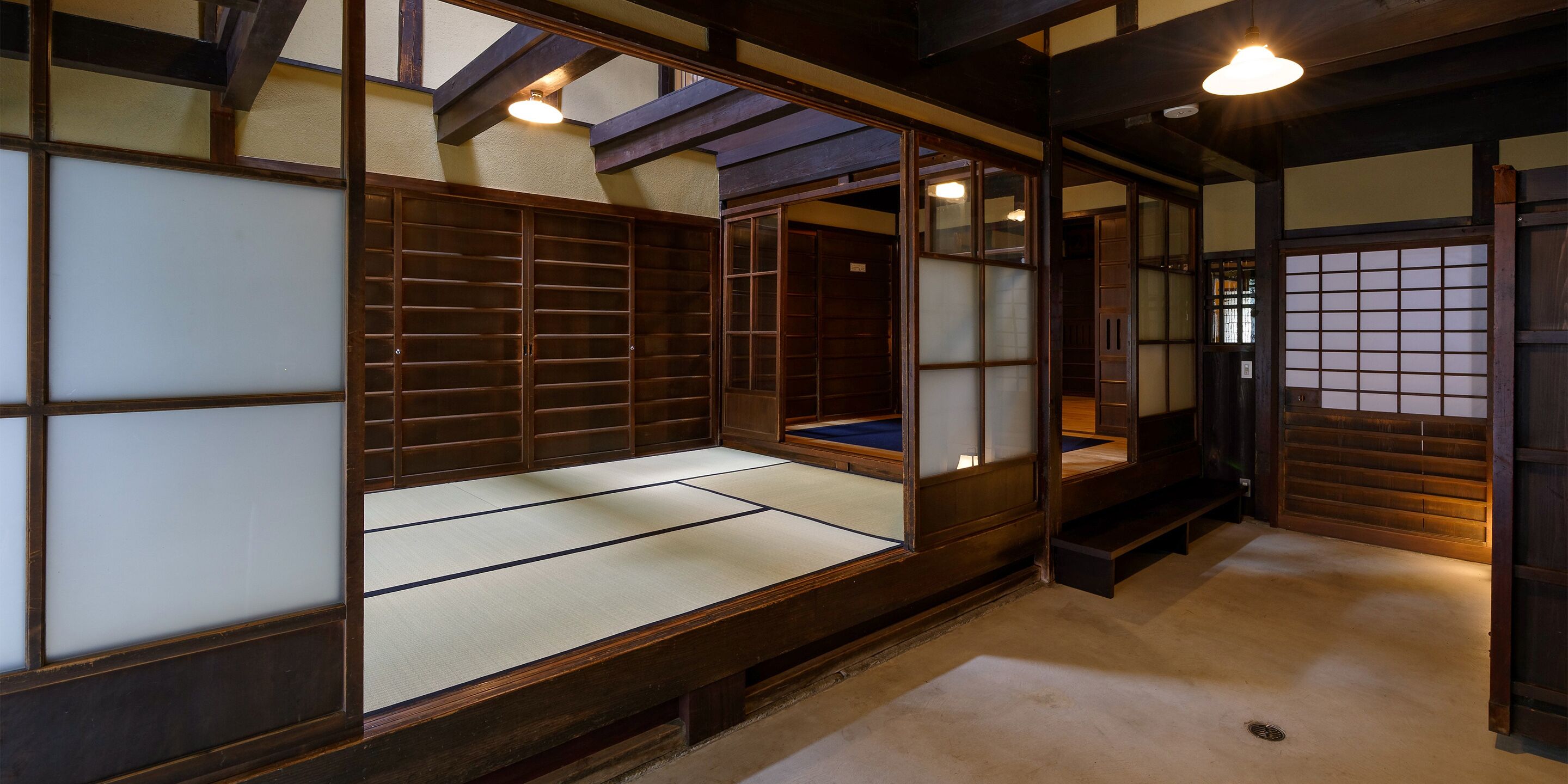 Une pièce de style japonais traditionnel, avec un sol recouvert de tatamis, des portes coulissantes et des poutres en bois.