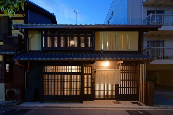 A traditional Japanese house with a tiled roof, wooden sliding doors, and a small porch area.