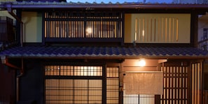 A traditional Japanese building with a tiled roof, wooden sliding doors, and a small statue.