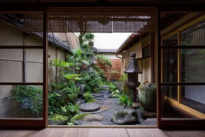 A traditional Japanese garden with a stone path, rocks, and various plants.